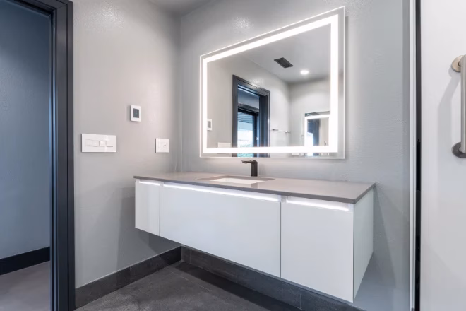 A floating vanity beneath a mirror with LED lighting