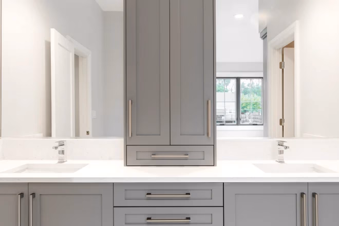 A gray vanity in a large luxurious bathroom with granite counter tops and chrome fixtures