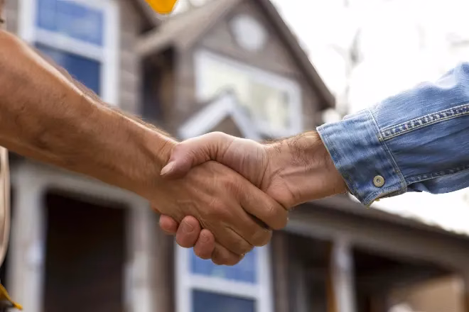 A home addition contractor and homeowner shaking hands to minimize disruption home addition