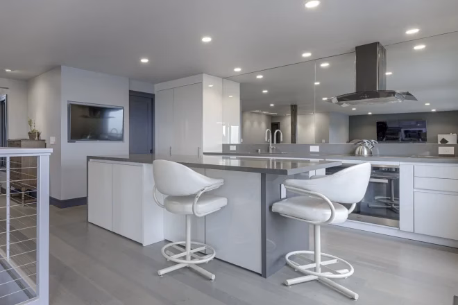 A kitchen island with recessed ceiling lights above it