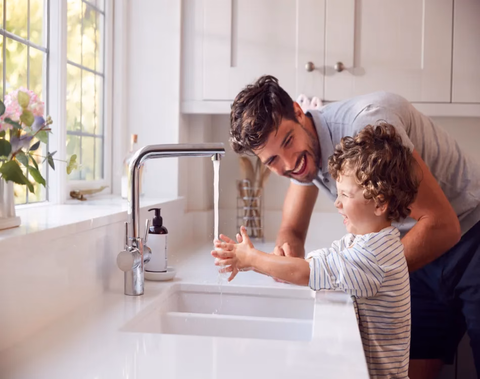 A man and a young boy test their new kitchen faucet.