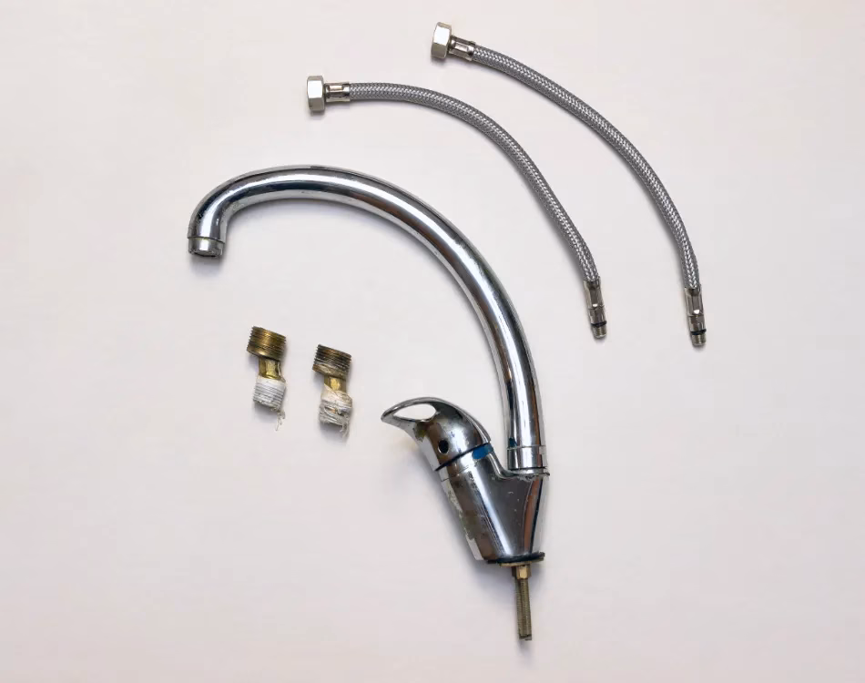 An old kitchen faucet disassembled on a white background.
