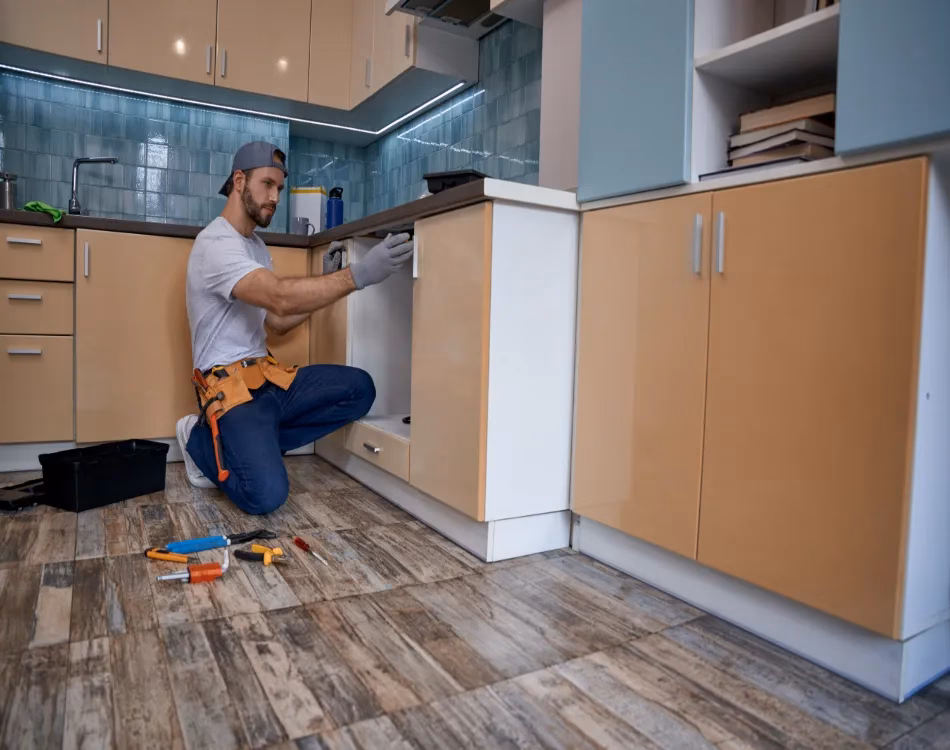 Young worker measuring drawer in kitchen.